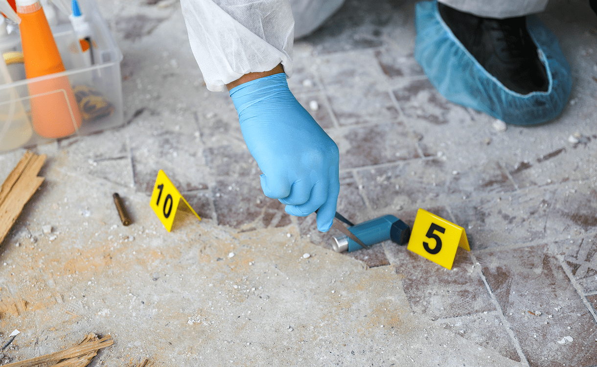 Gloved hand collecting sample at crime scene
